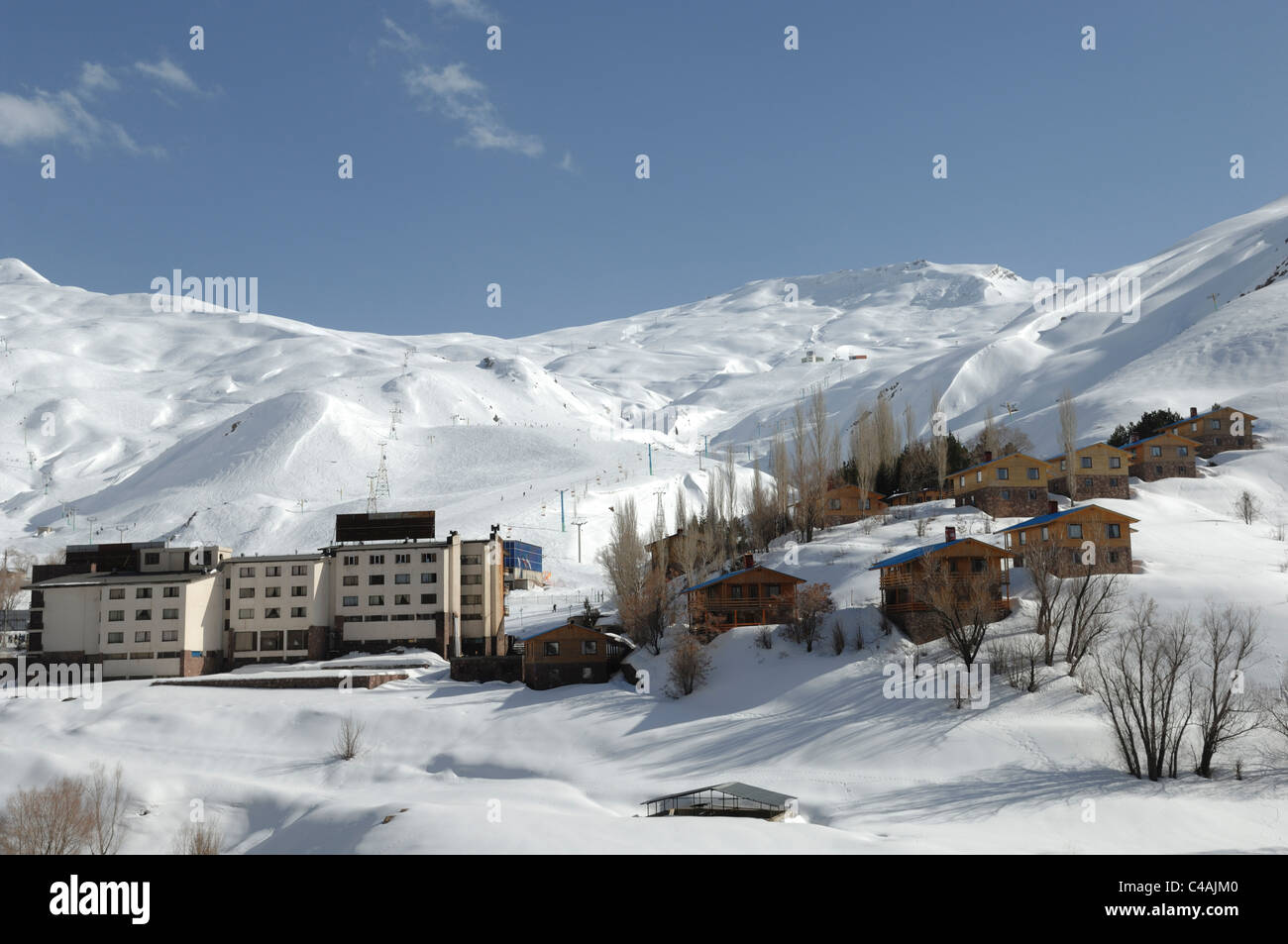 Dizin ski resort in Alborz montagne di Iran sotto un cielo blu e la caduta di neve Foto Stock