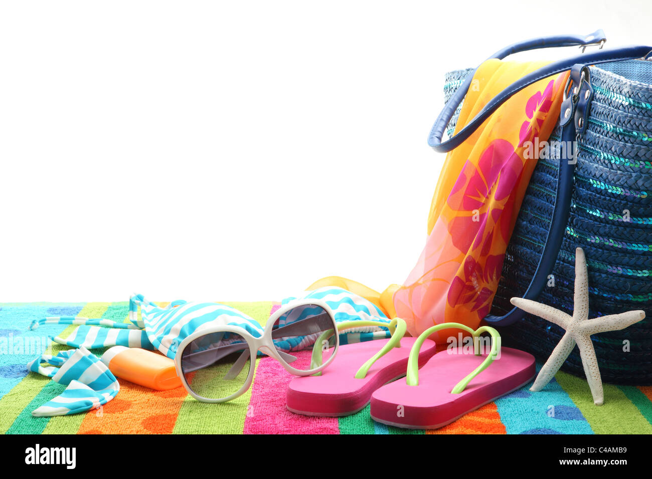 Accessori in spiaggia con costume da bagno,occhiali da sole,scialle e flip flop su sfondo bianco. Foto Stock