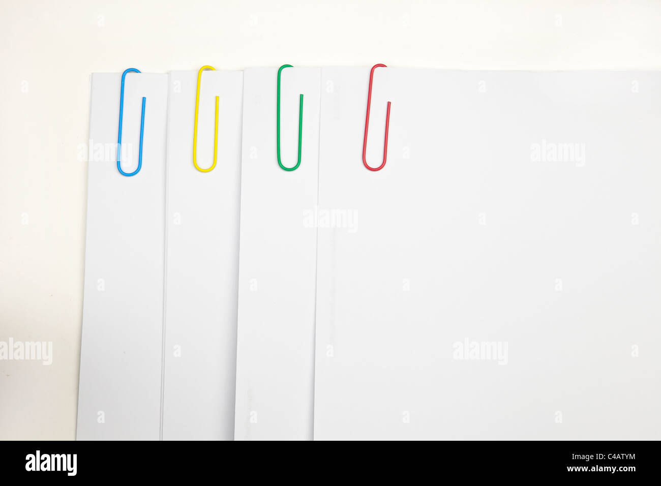 Clip di carta in quattro diversi colori - blu, verde, giallo, rosso, mantenere il bianco insieme fogli di carta Foto Stock