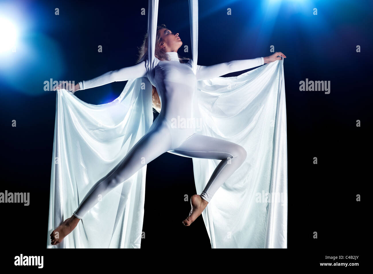 Giovane donna ginnasta. Su sfondo nero con effetto flash. Foto Stock