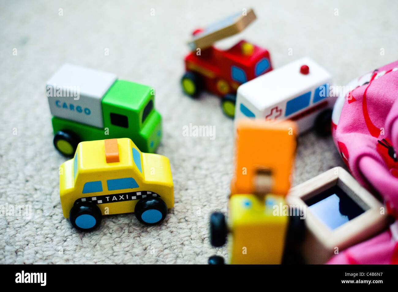 Un piccolo gruppo di bambini di legno verniciato i veicoli giocattolo su un tappeto di folle. Foto Stock