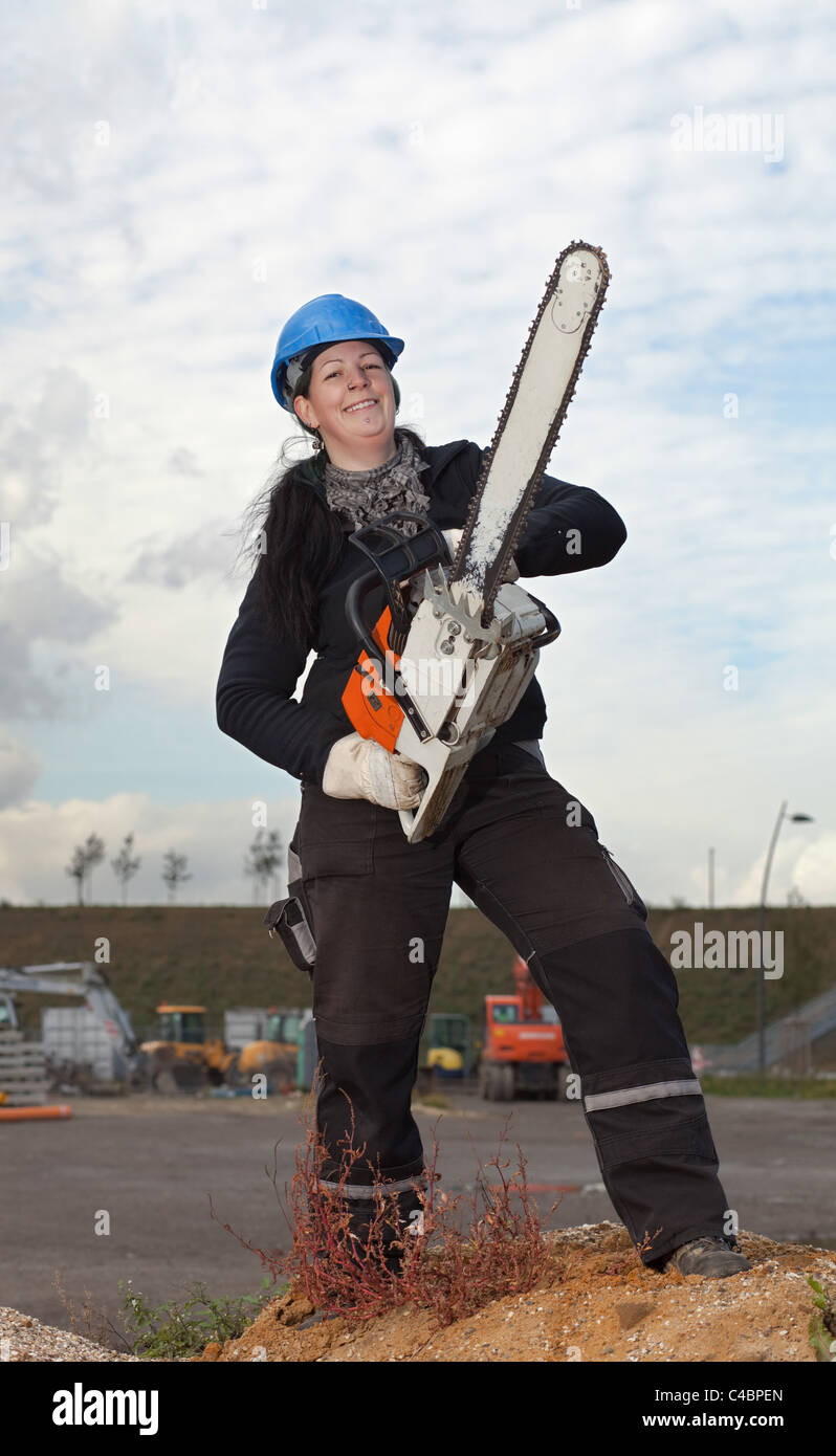 Lavoratore di sesso femminile che in abbigliamento da lavoro e di  compressori hardhat trattiene grandi chainsaw Foto stock - Alamy