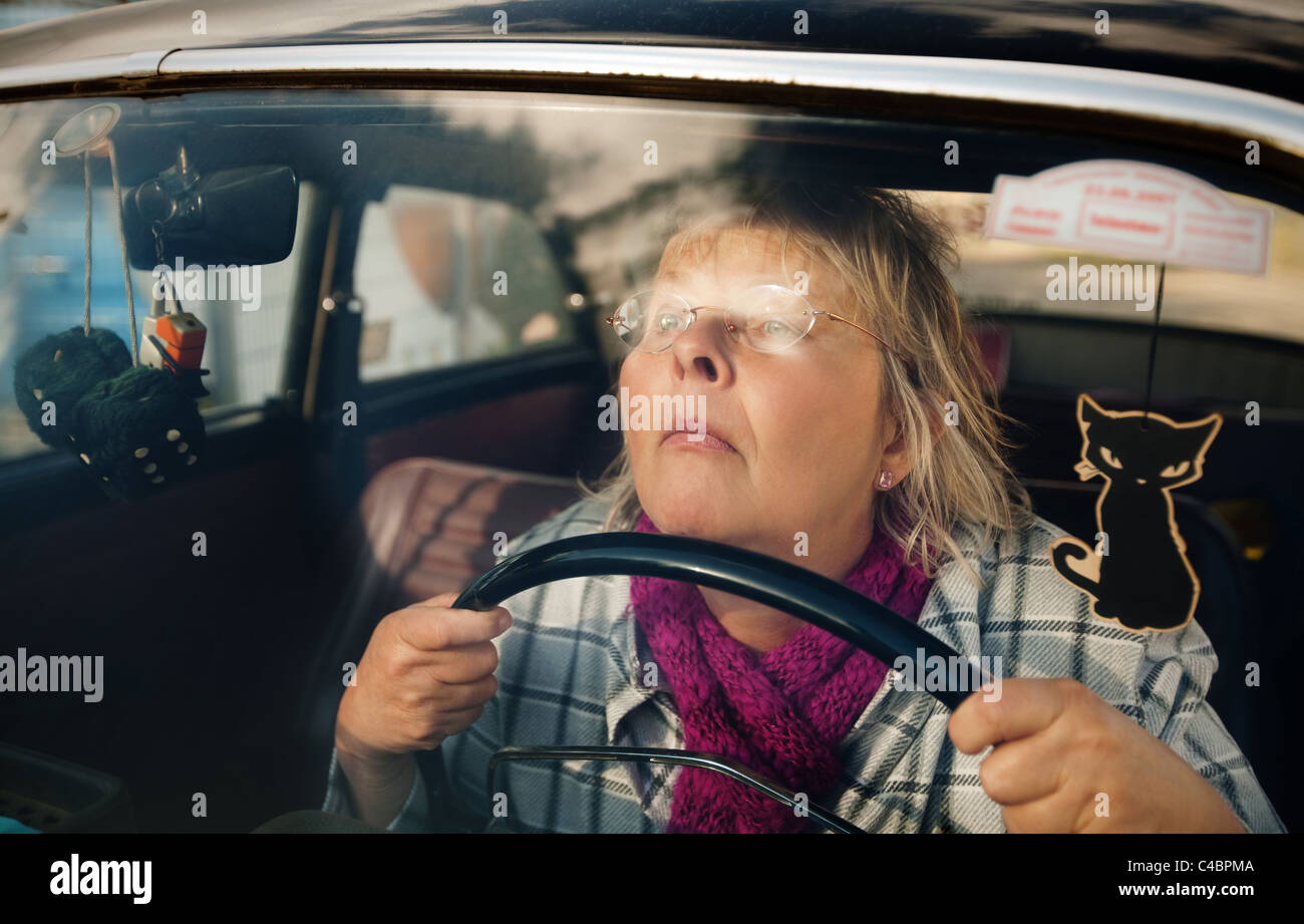 Concentrato e ha sottolineato il senior donna alla guida di un'auto oldtimer Foto Stock