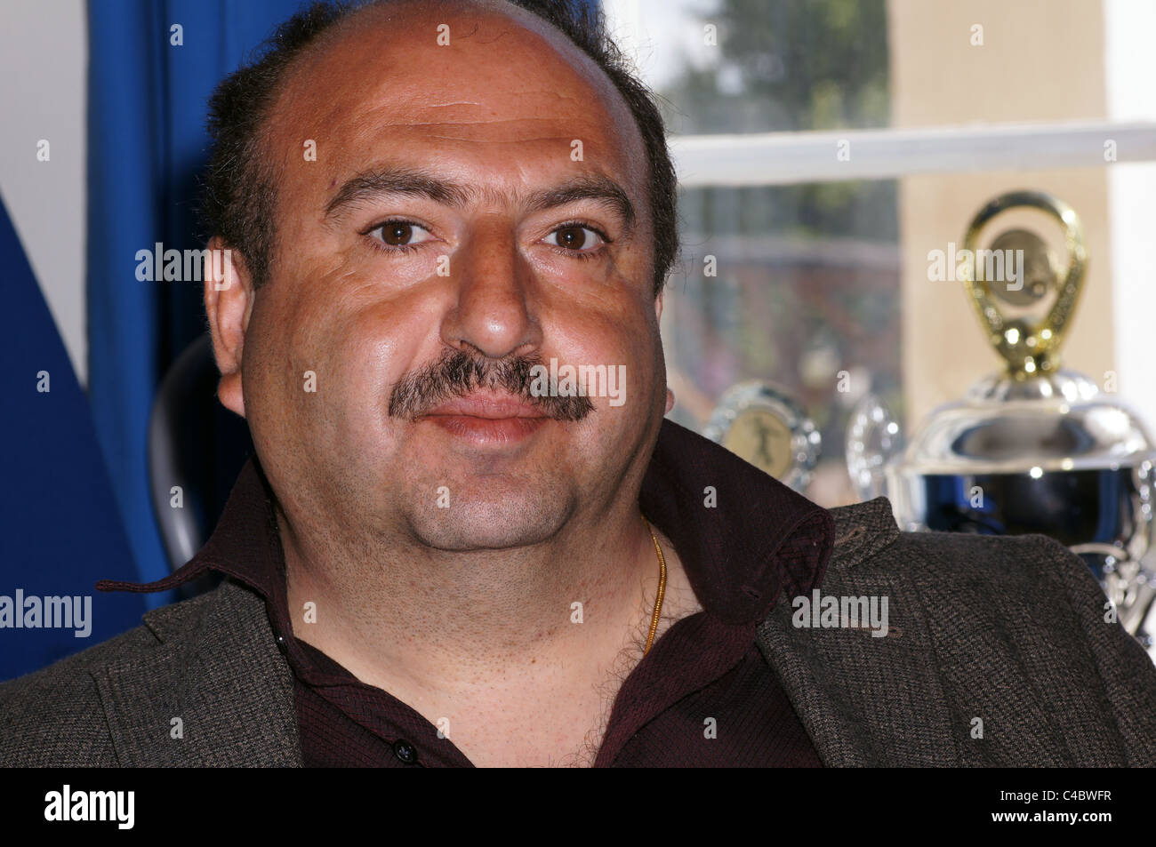 L uomo dal Medio Oriente che guarda nella telecamera con premio sport in background Foto Stock