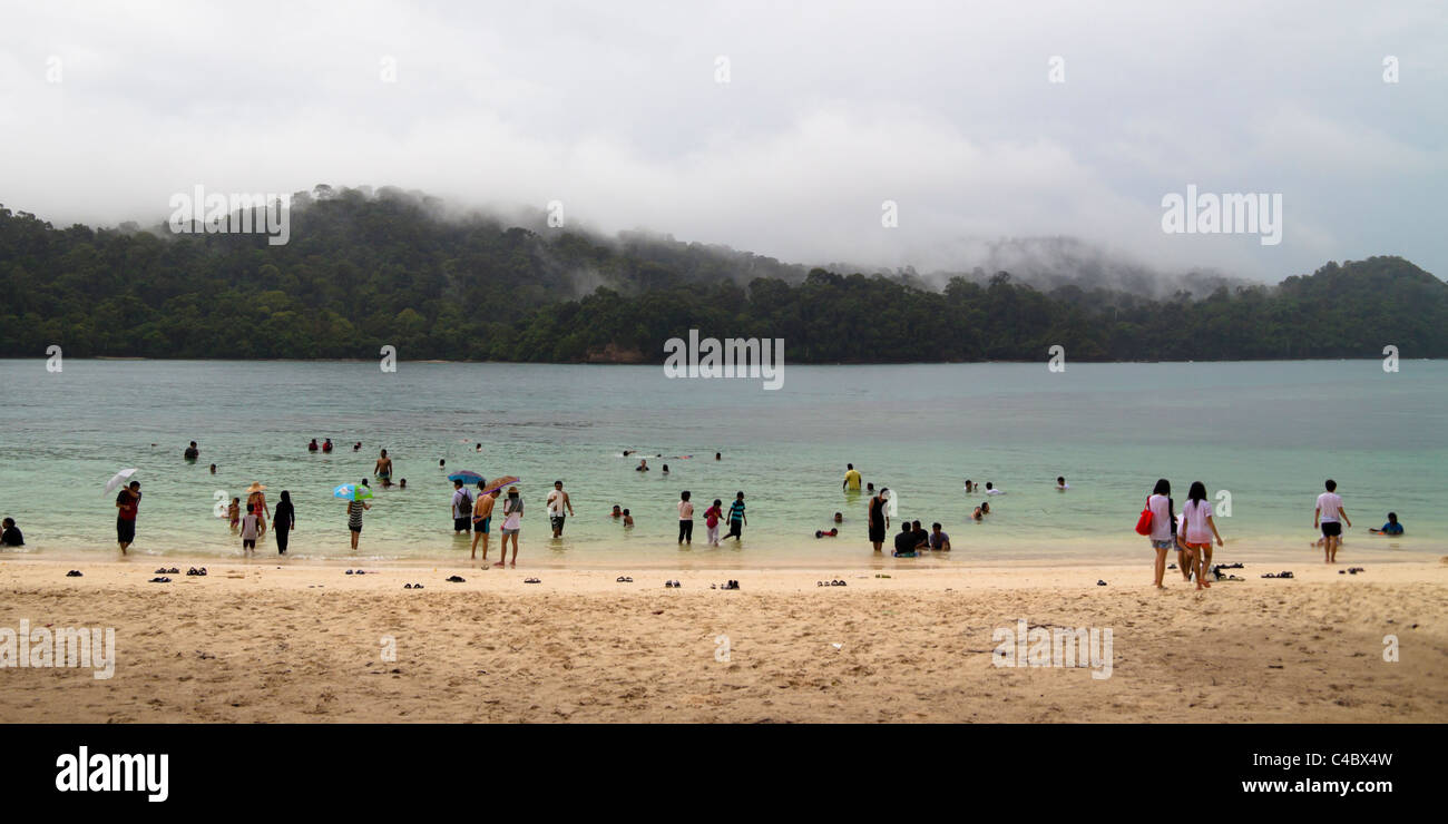 Le persone che si godono la spiaggia tropicale durante la giornata piovosa a Langkawi - Malaysia. Foto Stock