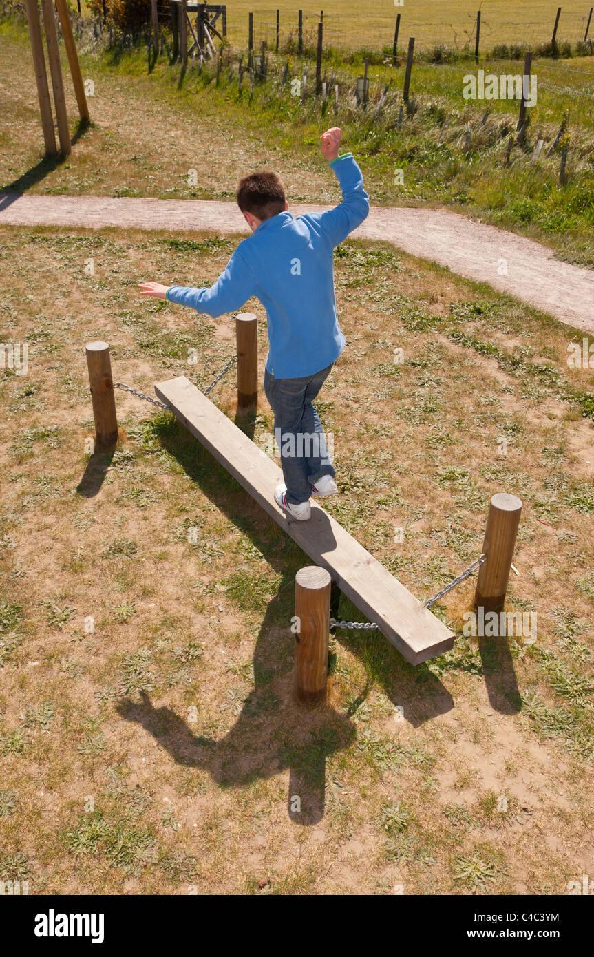 Un ragazzo di undici anni il bilanciamento al parco giochi in Westleton , Suffolk , Inghilterra , Inghilterra , Regno Unito Foto Stock