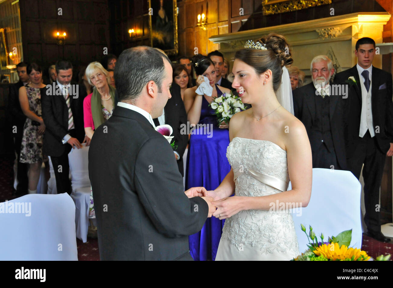 Un paesaggio immagini scattate durante un matrimonio civile cerimonia con la sposa e lo sposo lo scambio di anelli nella parte anteriore della loro famiglia. Foto Stock