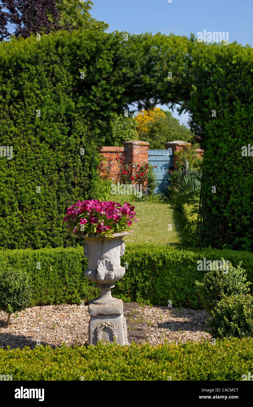 Scatola di copertura e yew hedge arch in giardino con il pezzo centrale urna che conduce al cancello del giardino Foto Stock