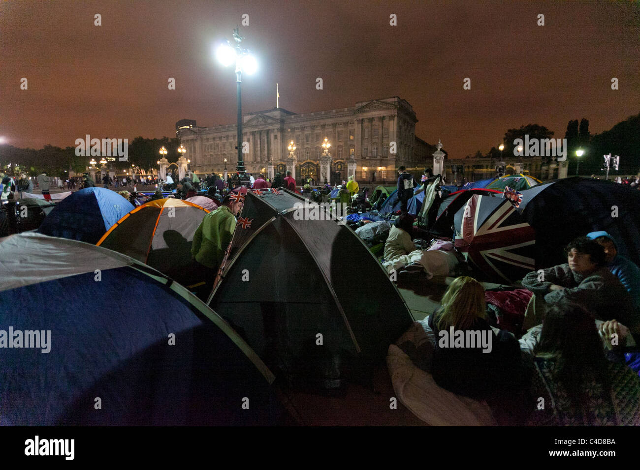 Folla festante camping fuori di fronte a Buckingham Palace la notte prima del matrimonio regale del principe William e Kate Middleton Foto Stock