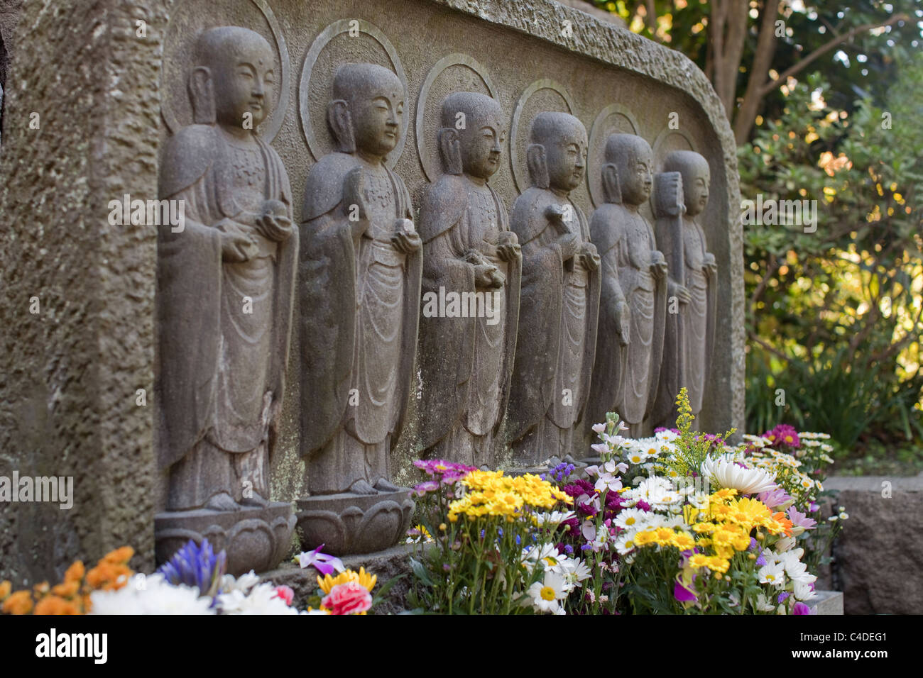 Muro di pietra con Jizo sculture e fiori freschi a Hase-dera tempio a Kamakura, Giappone. Foto Stock