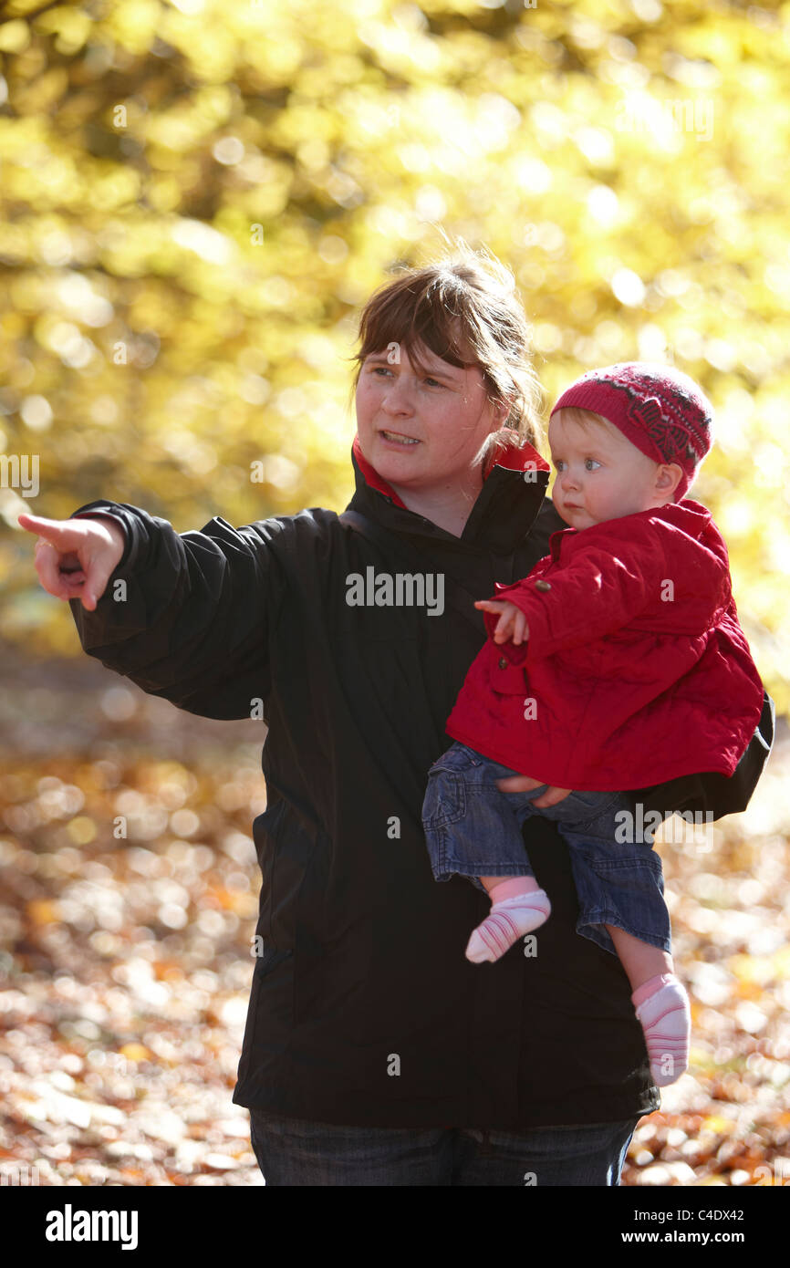 8 mese fa bambina nel parco in autunno con le foglie intorno Foto Stock