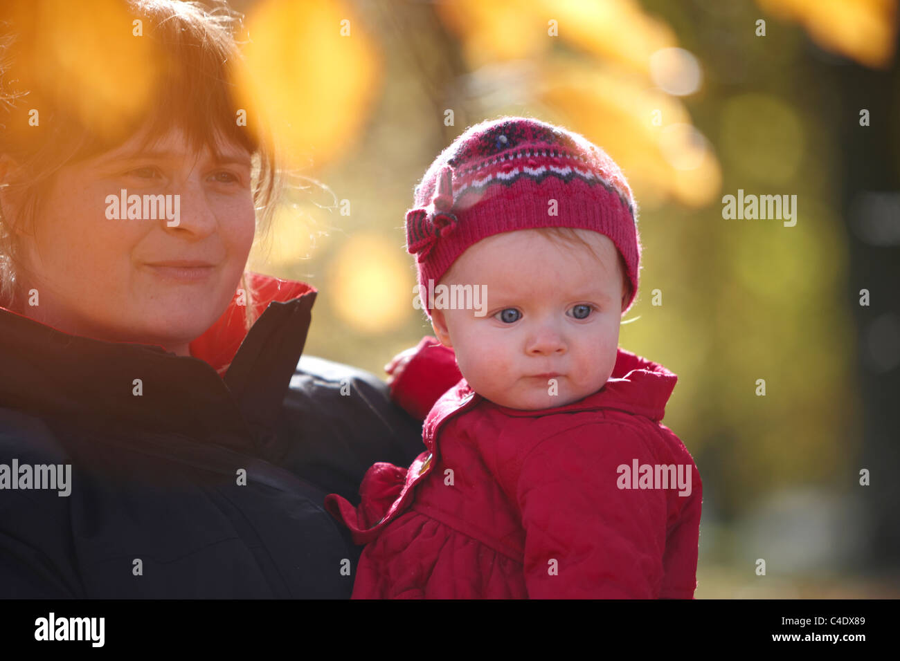 8 mese fa bambina nel parco in autunno con le foglie intorno Foto Stock