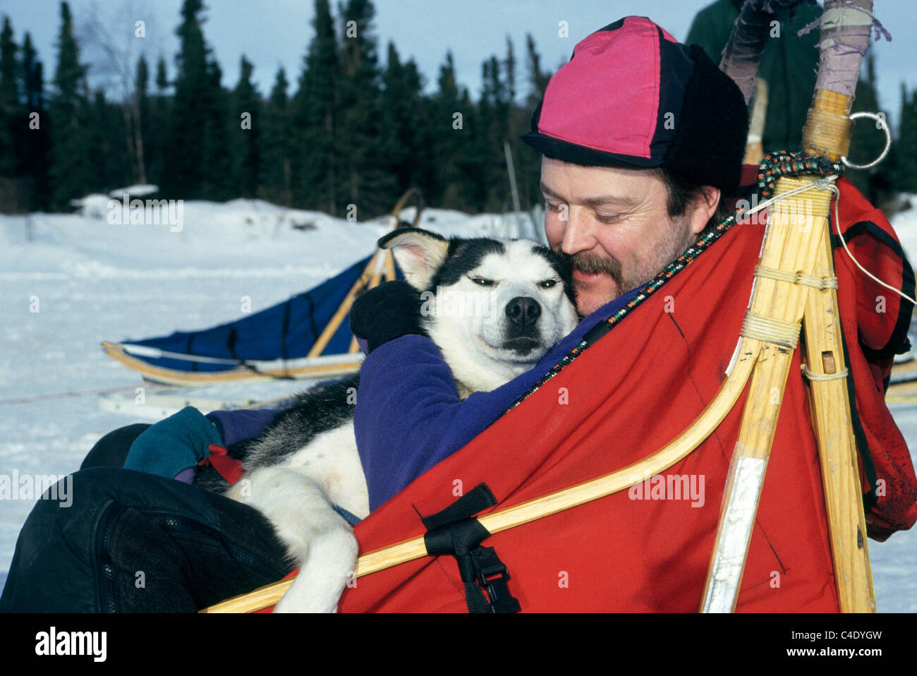 Un affettuoso musher appoggia insieme con il suo husky di piombo in un dogsled dopo la formazione per il sentiero Iditarod Sled Dog Race vicino a Anchorage in Alaska,, Stati Uniti d'America. Foto Stock