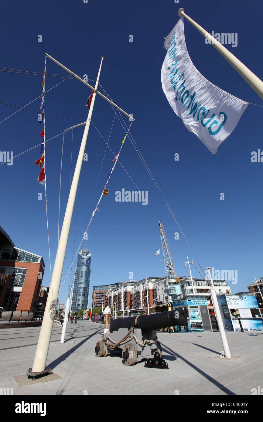 Città di Portsmouth, Inghilterra. Bandiera in corrispondenza del montante del Portsmouth Gunwharf Quays con il numero di una torre nel lontano sullo sfondo. Foto Stock