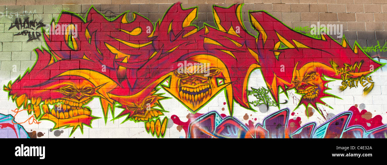 Un malvagio cercando graffiti murali male con facce dipinte in tutta l'immagine Foto Stock