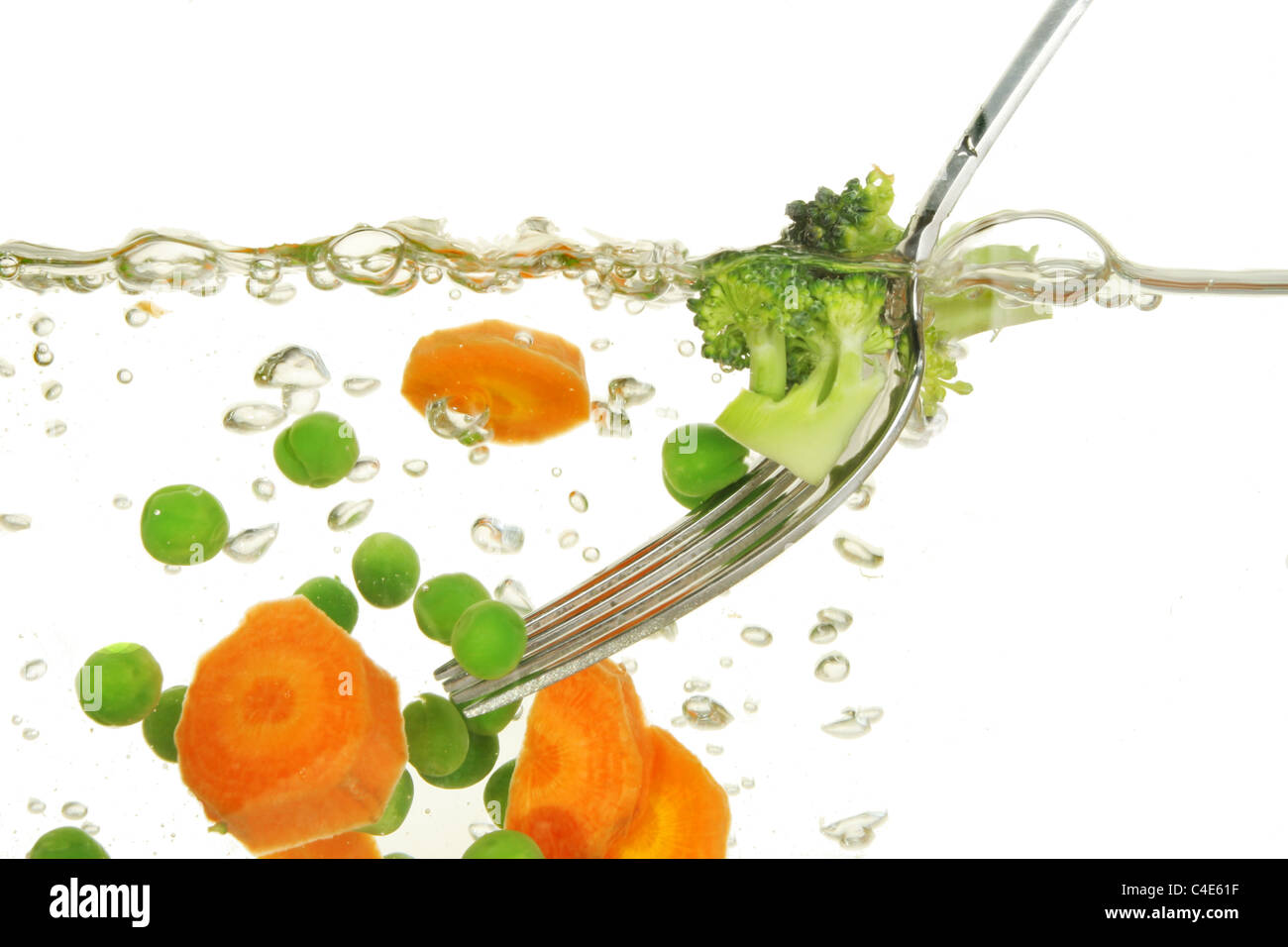Carote, piselli e verdure brocolli cottura in acqua bollente con un acciaio inossidabile forcella Foto Stock
