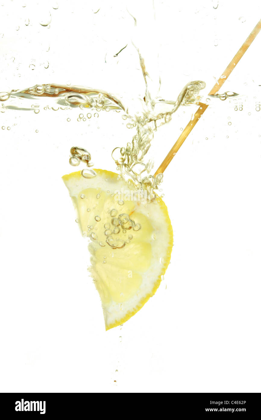 Primo piano di una fetta di limone schizzi in acqua circondato da bolle Foto Stock