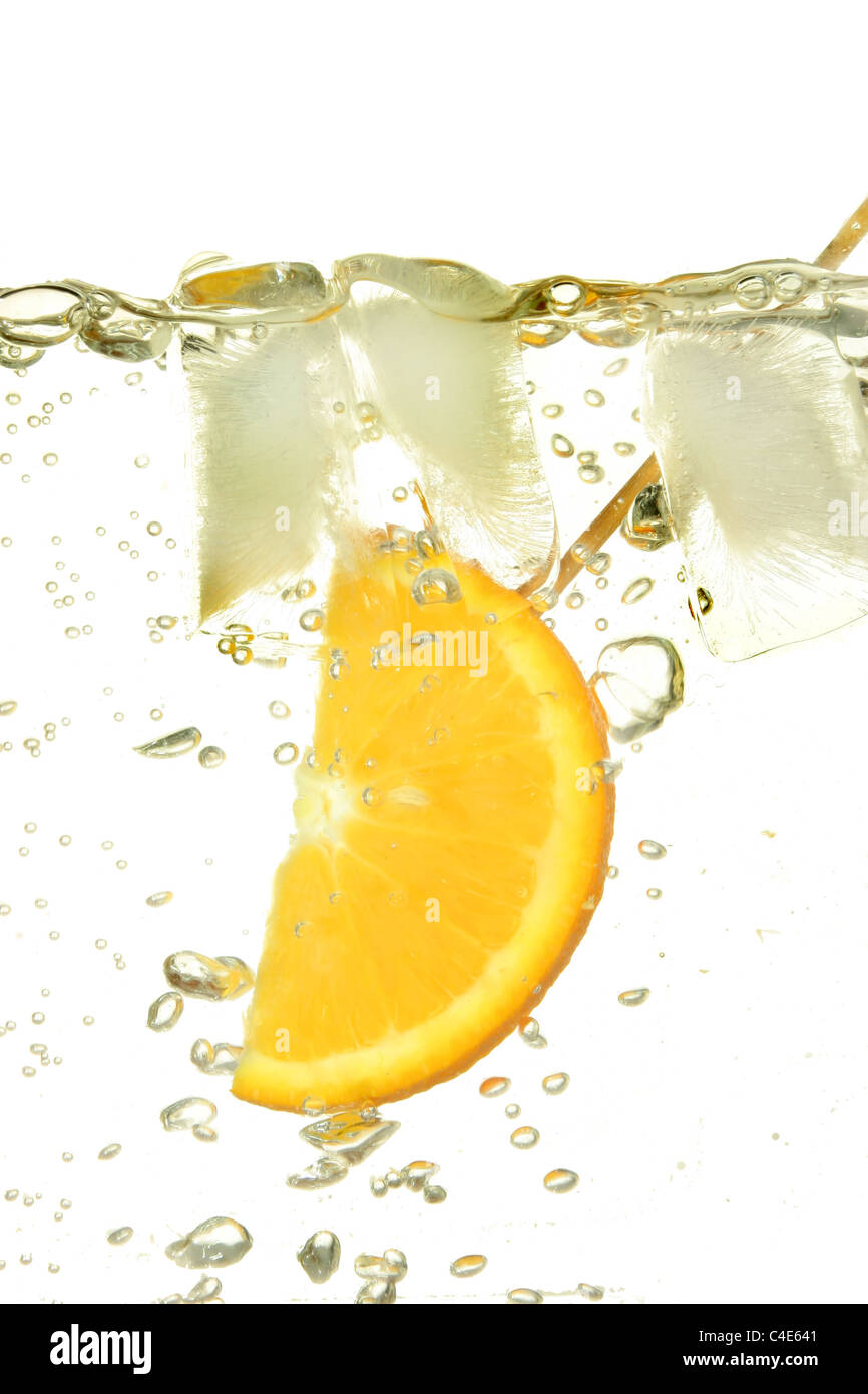 Fettina di arancio con ghiaccio circondato da bolle in acqua Foto Stock