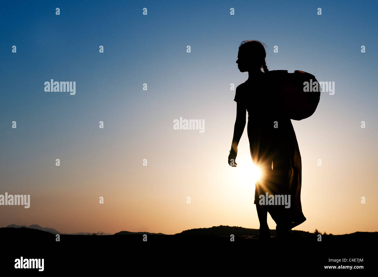 Rurale villaggio indiano ragazza che porta una pentola di acqua al tramonto. Silhouette. Andhra Pradesh, India Foto Stock