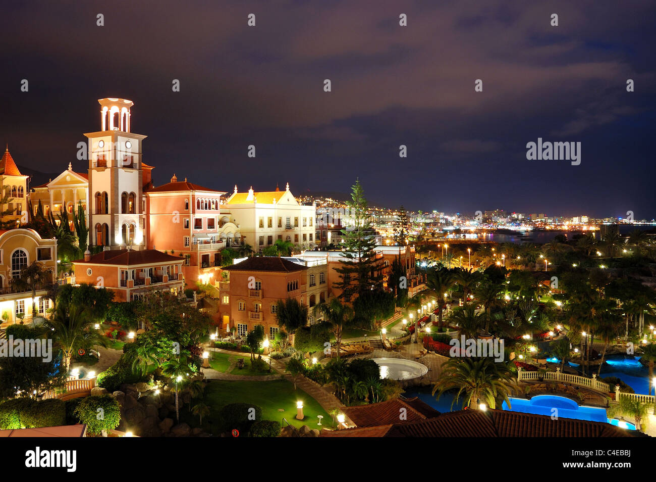 Illuminazione notturna di hotel di lusso durante il tramonto e Playa de las Américas a sfondo, isola di Tenerife, Spagna Foto Stock