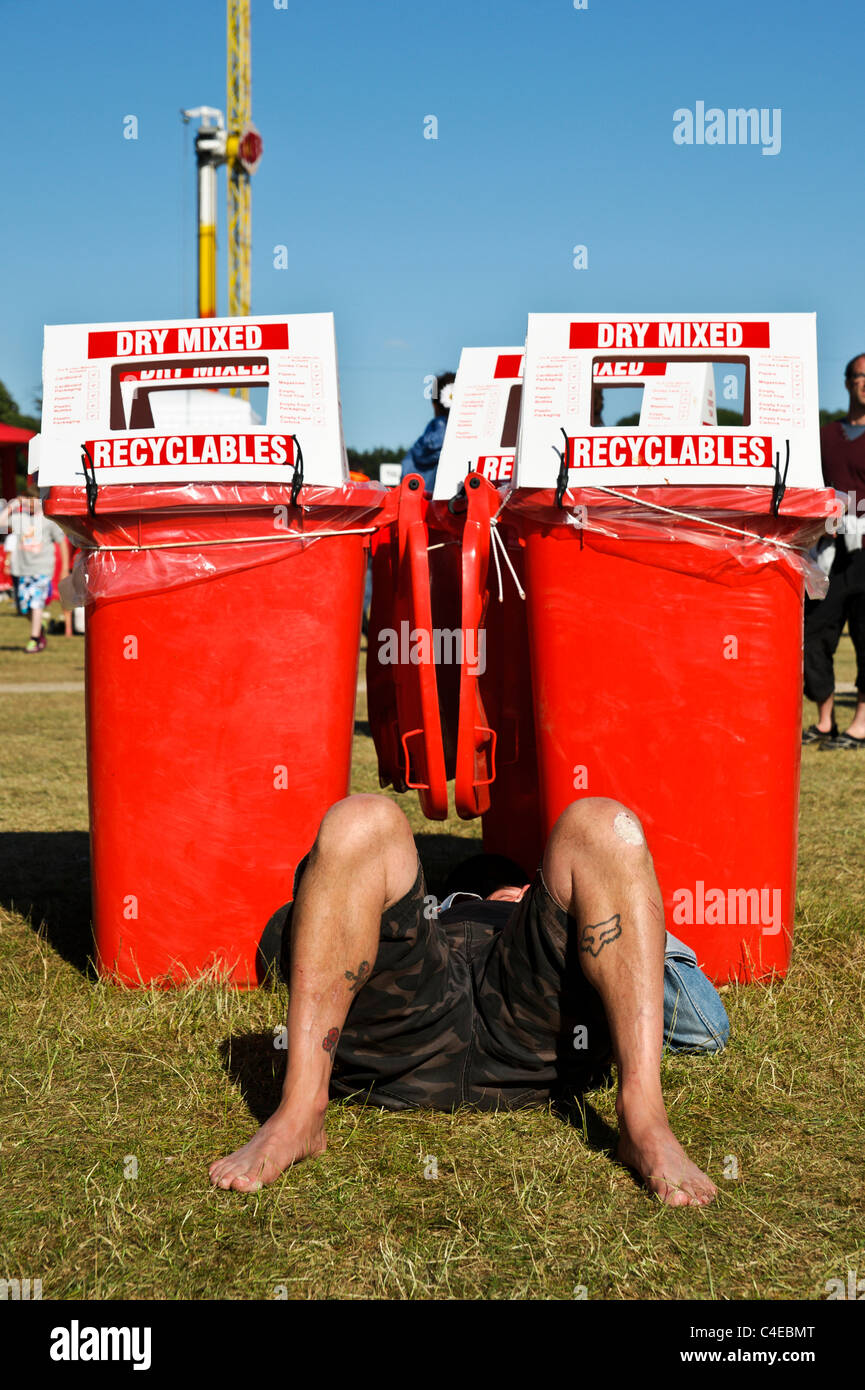 Un uomo si trova di fronte dei cassonetti per il riciclaggio a Isle of Wight Festival 2011, Newport il 11 giugno 2011. Foto di Julie Edwards Foto Stock