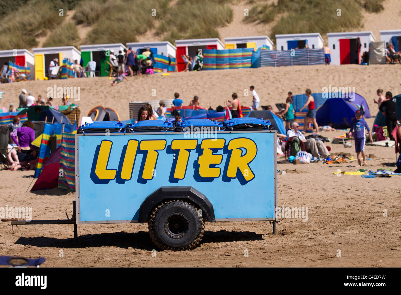 La folla e la plastica raccolta di lettiera carro rimorchio su la bandiera blu di sabbia costiera spiagge a Woolacombe Bay Beach, Devon, Regno Unito Foto Stock