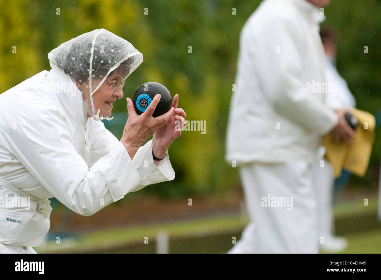 Attivo un pensionato femminile prende parte in una domenica pomeriggio Lawn Bowls corrispondono sotto la pioggia Foto Stock