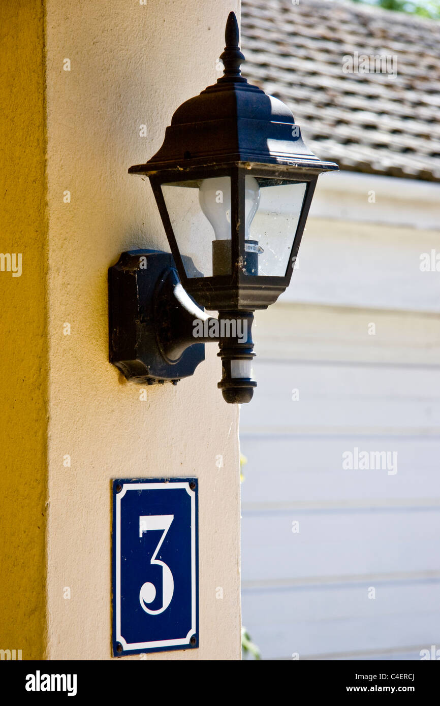 Lampada da parete con una casa con tre sotto di esso Foto Stock