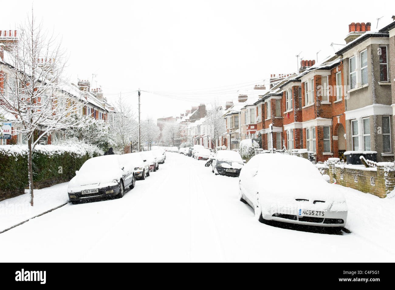 Coperta di neve auto in strada residenziale, London, Regno Unito Foto Stock