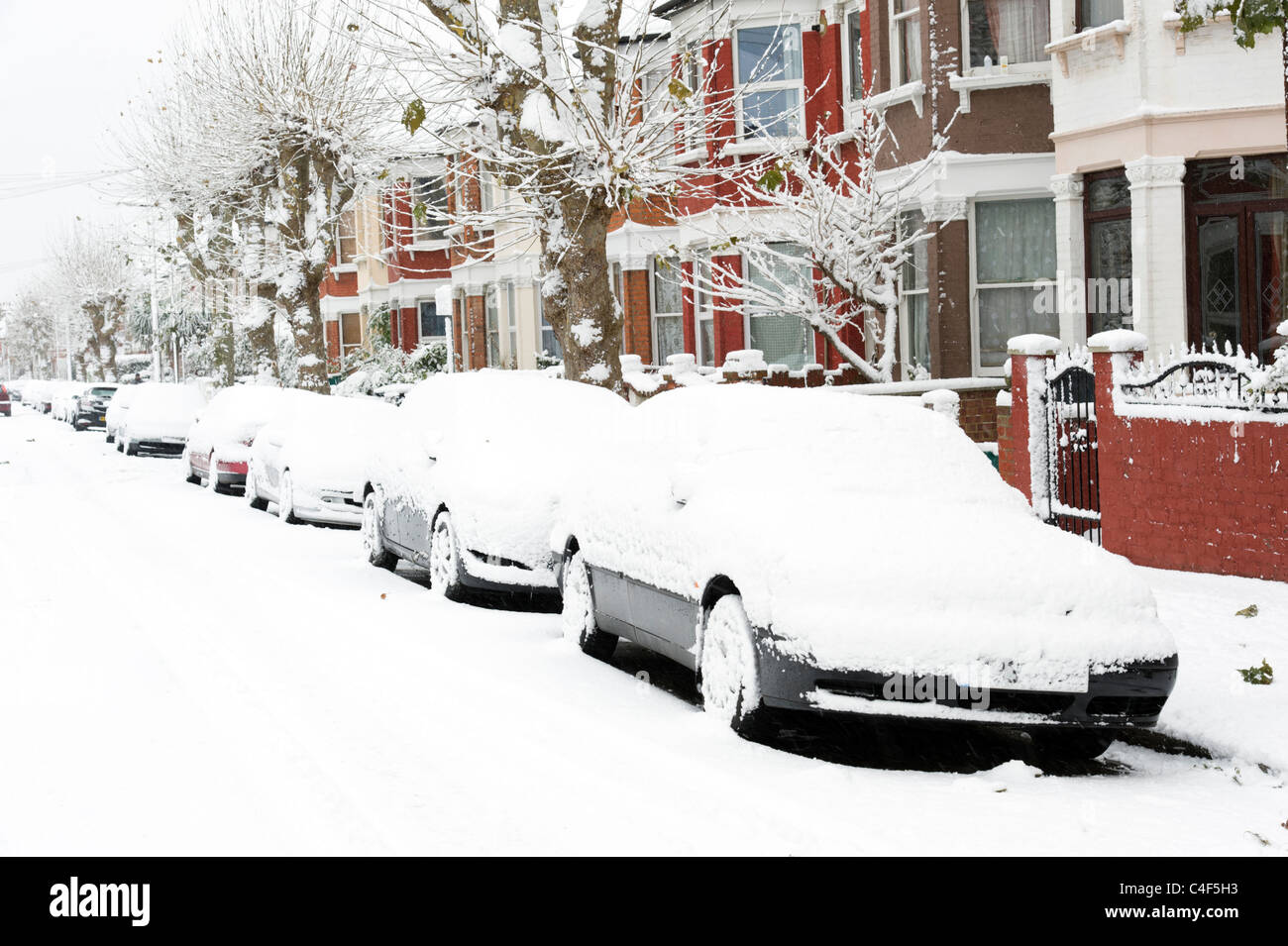 Coperta di neve auto in strada residenziale, London, Regno Unito Foto Stock