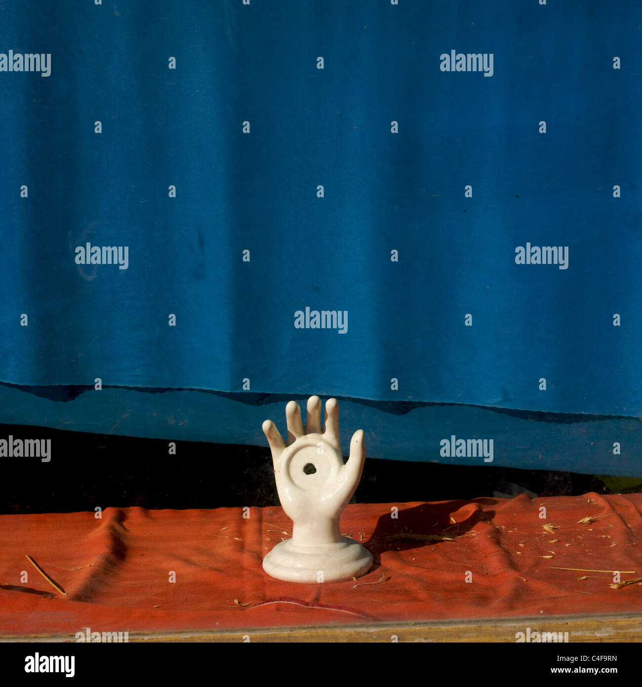 Scultura in ceramica decorativa in un negozio con intaglio circolare su sfondo blu e tessuto arancione Foto Stock