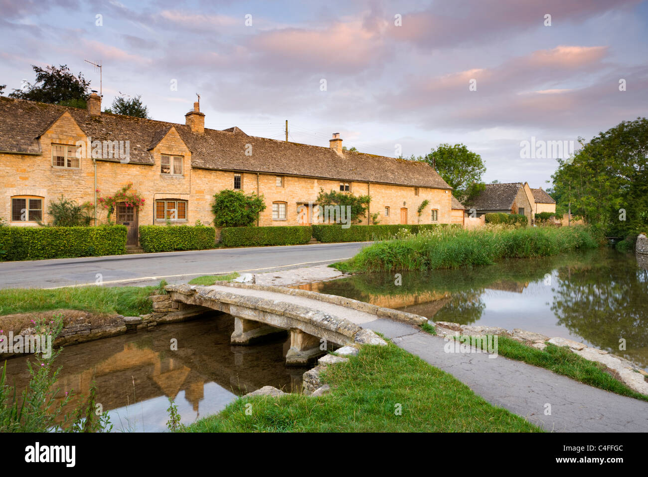 Cottage in pietra e il Footbridge in Cotswolds village di Lower Slaughter, Gloucestershire, Inghilterra. Foto Stock