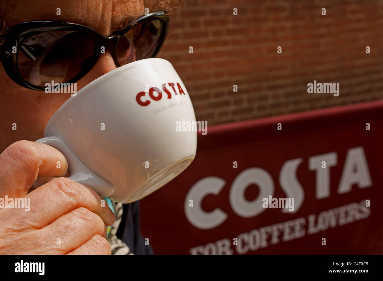 Donna di bere una tazza di caffè Costa Foto Stock