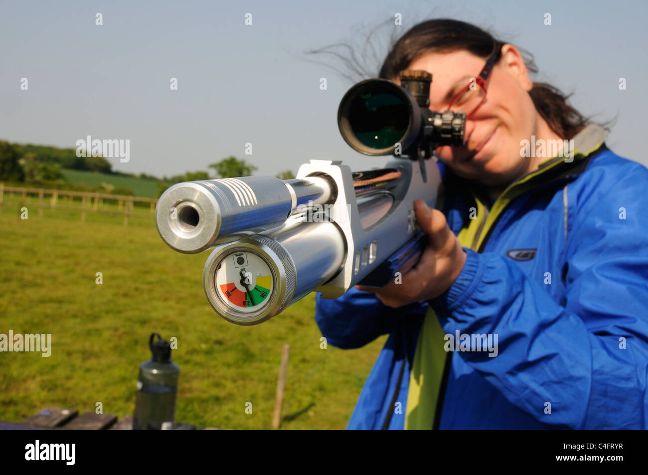 Una giovane donna che guarda attraverso i siti di un fucile ad aria compressa Foto Stock