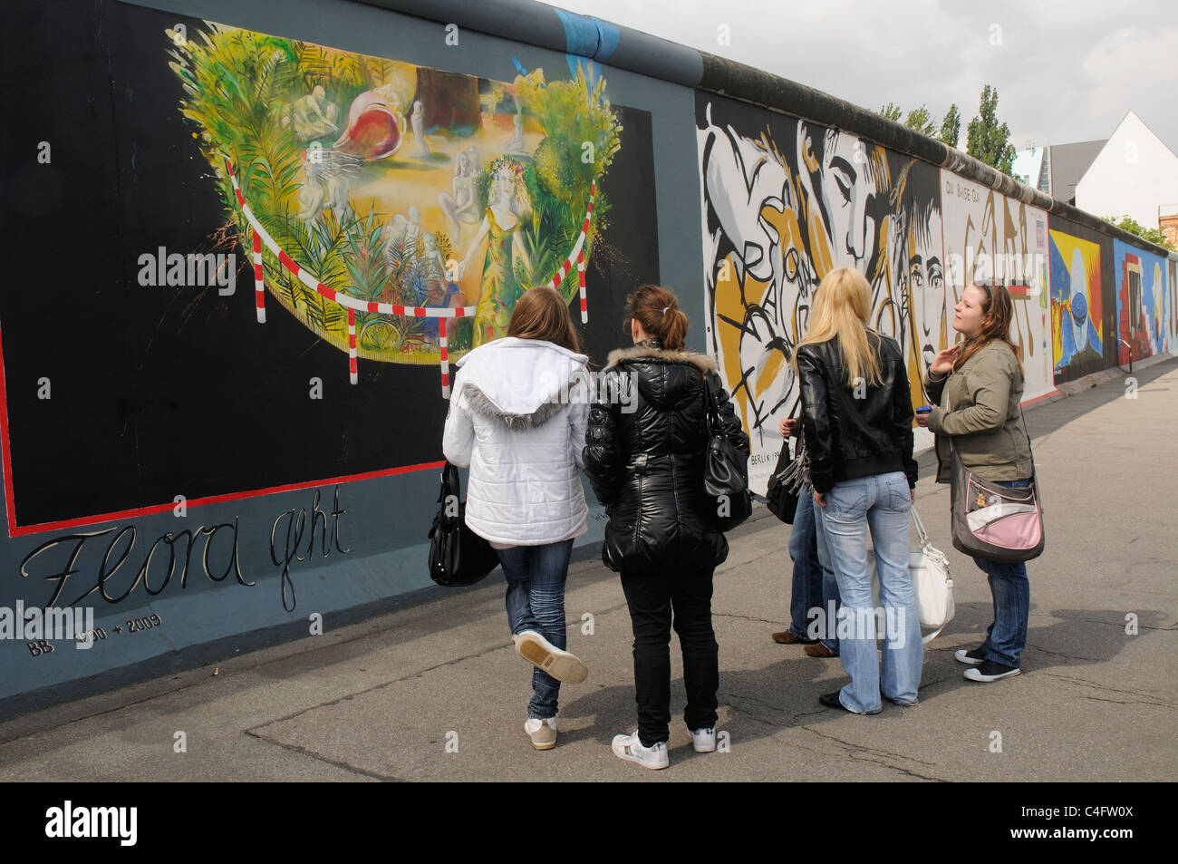 Un gruppo di persone che guardano i dipinti presso la East Side Gallery di Berlino Foto Stock