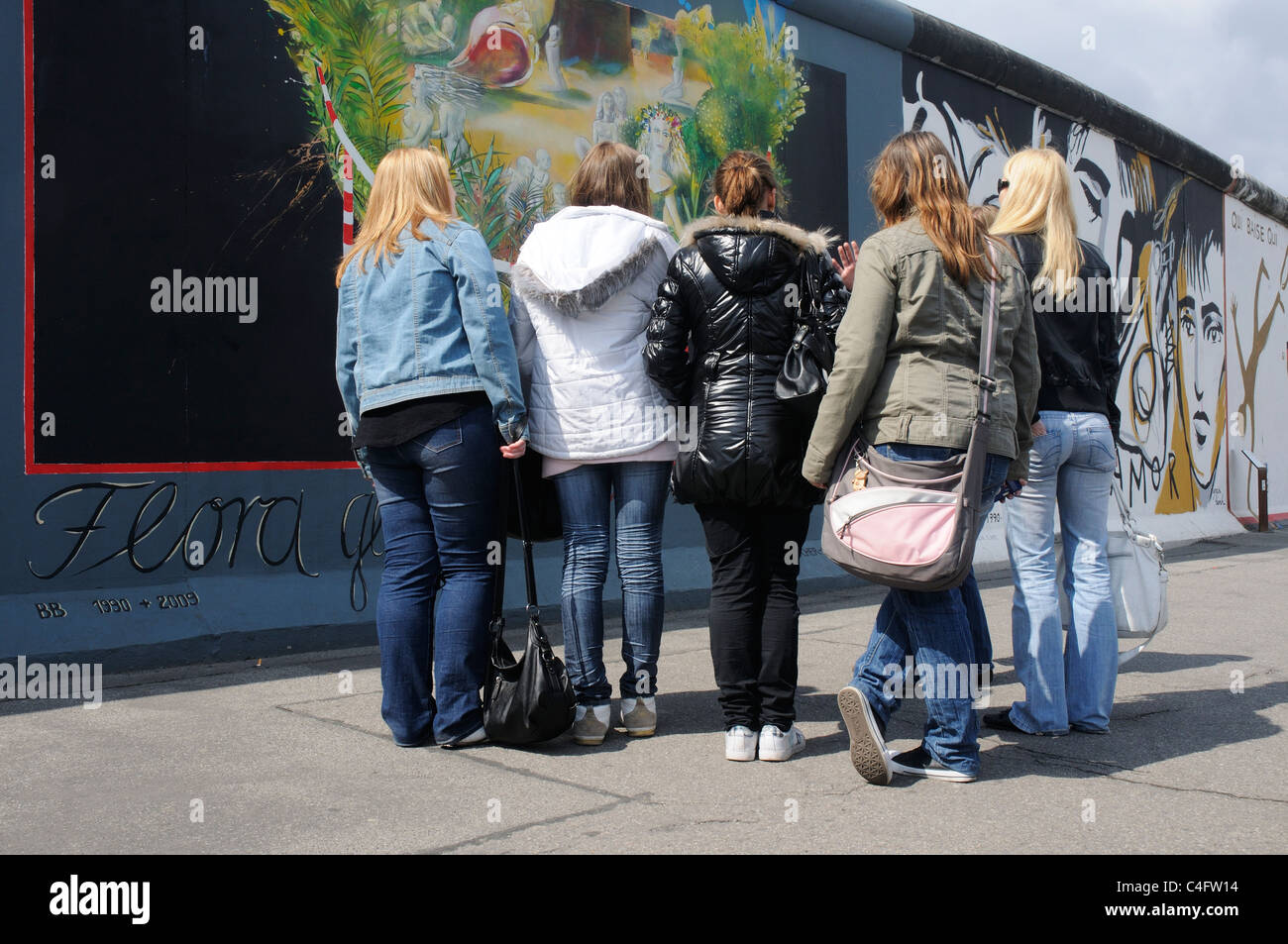 Un gruppo di persone che guardano i dipinti presso la East Side Gallery di Berlino Foto Stock