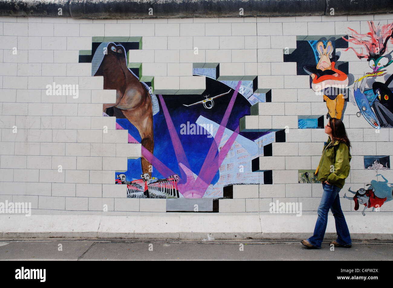 Una ragazza cammina passato le copertine degli album dei Pink Floyd il muro dipinto sul muro di Berlino presso la East Side Gallery Foto Stock