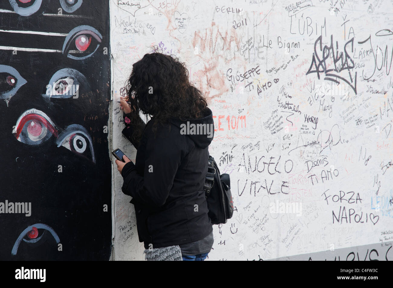 Una ragazza scrivere sul muro di Berlino Foto Stock