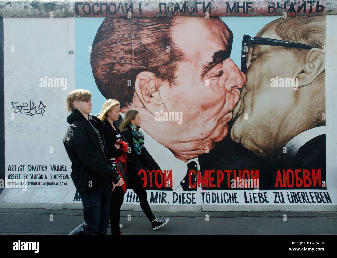 La gente a piedi dal famoso dipinto di Honecker Brezhnev e baciare francese sul muro di Berlino a Eastside Gallery Berlin Foto Stock