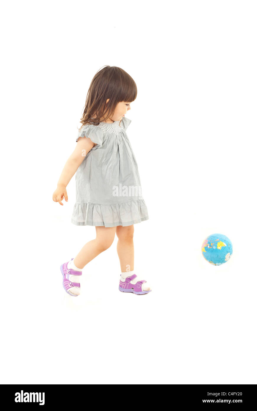 Il Toddler girl in azione giocando a calcio con globo mondo isolato su sfondo bianco Foto Stock