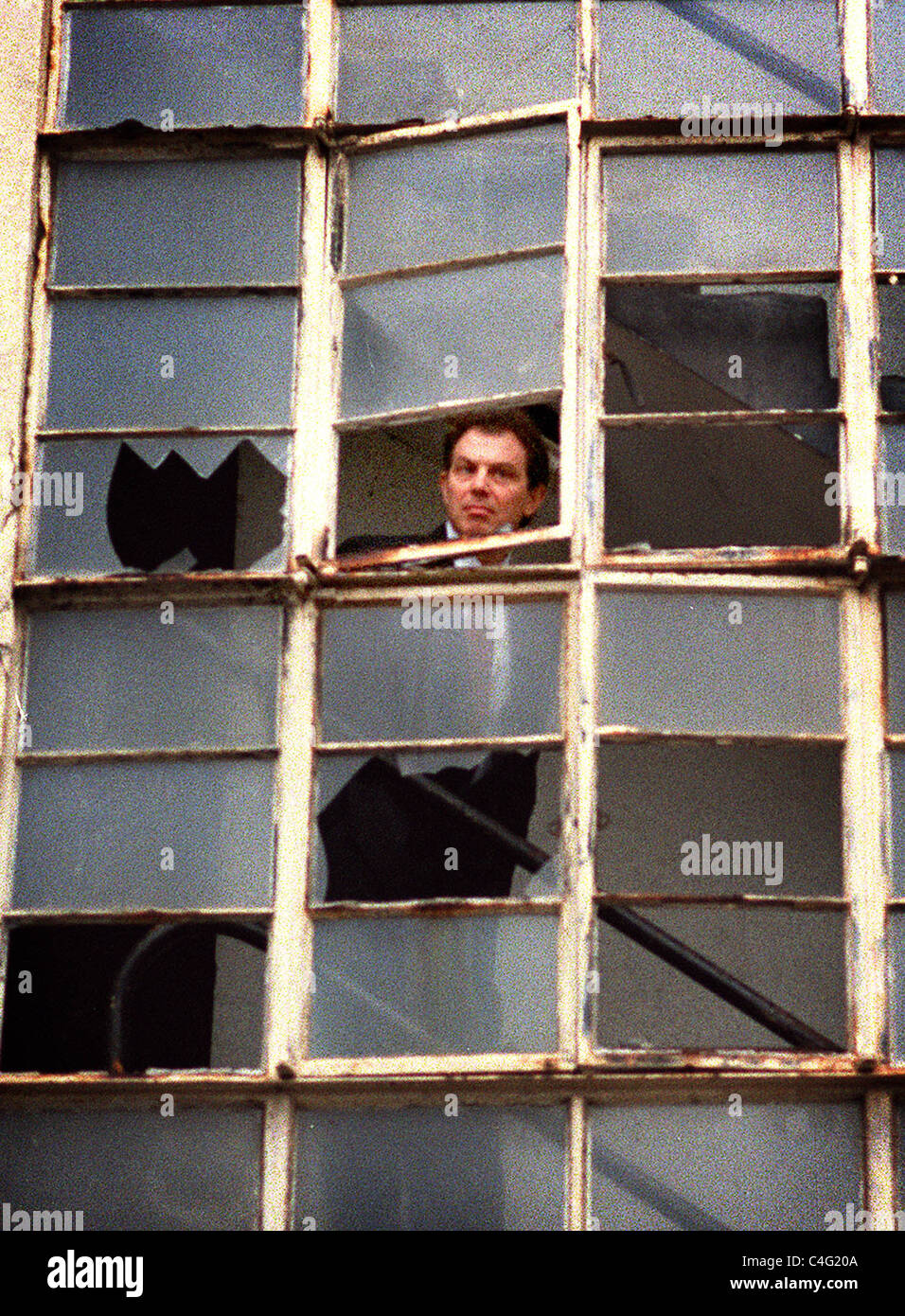 Leader del partito laburista di Tony Blair guarda fuori attraverso una finestra rotta della corsa verso il basso porta Portland blocco di appartamenti in Hove Foto Stock