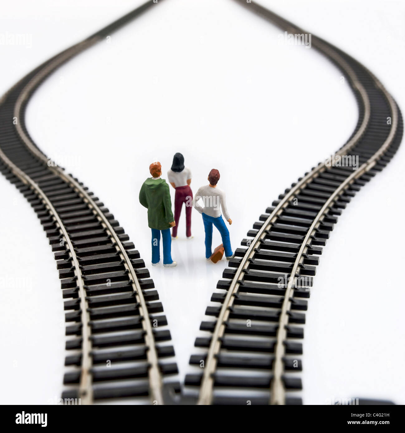 Giovani figurine tra due sentieri che conducono in diverse direzioni, immagine simbolica per prendere decisioni. Foto Stock