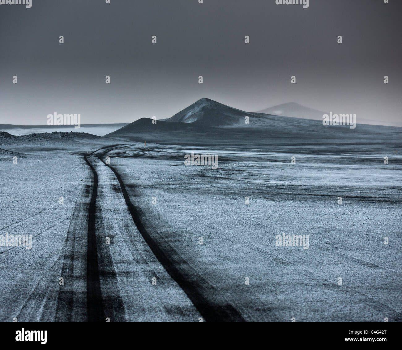 Luce neve sulle ceneri del paesaggio riempito wth tracce jeep fuoristrada. Highlands Centrali, Islanda Foto Stock