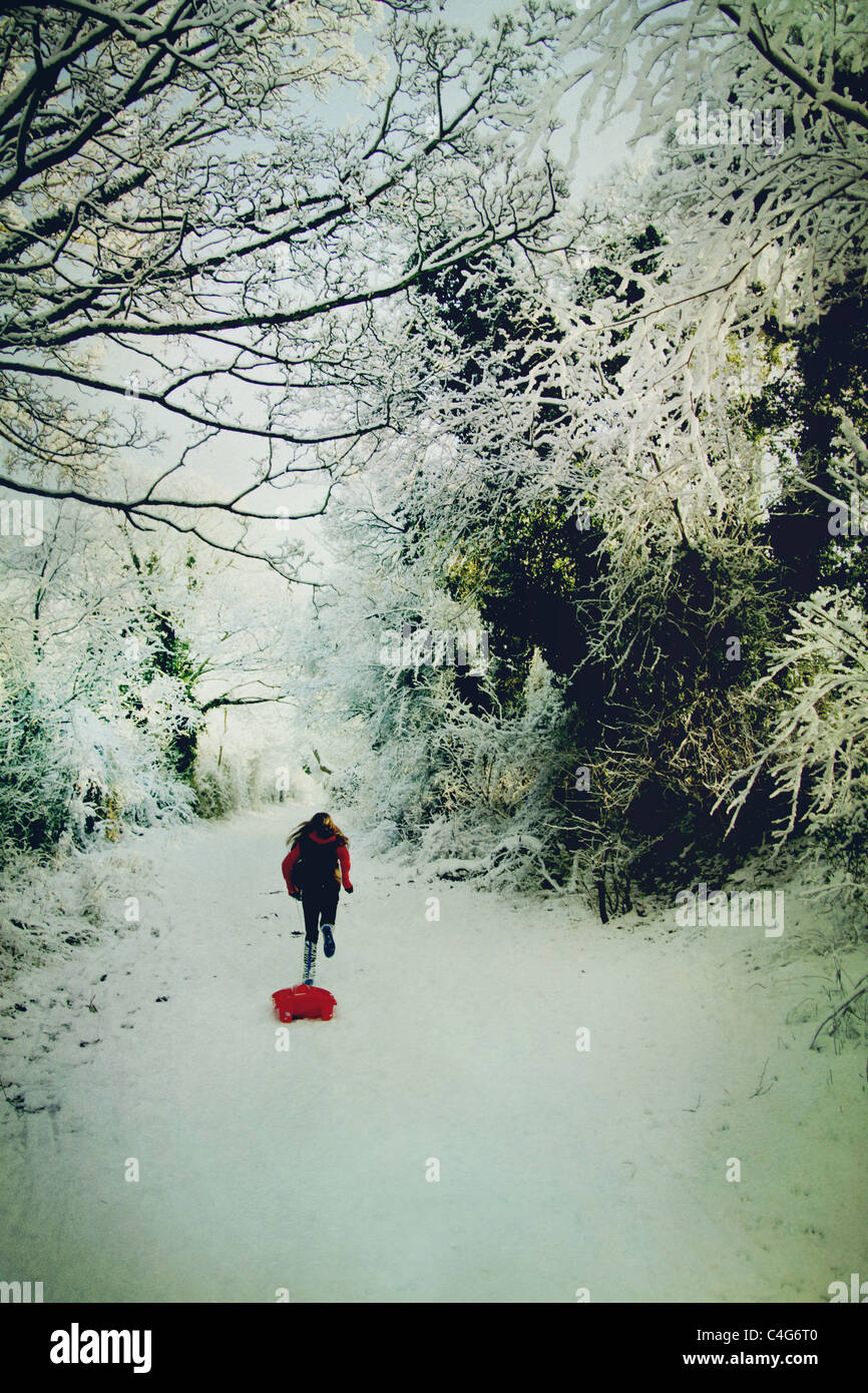 Ragazza che corre sulla neve con lo slittino Foto Stock