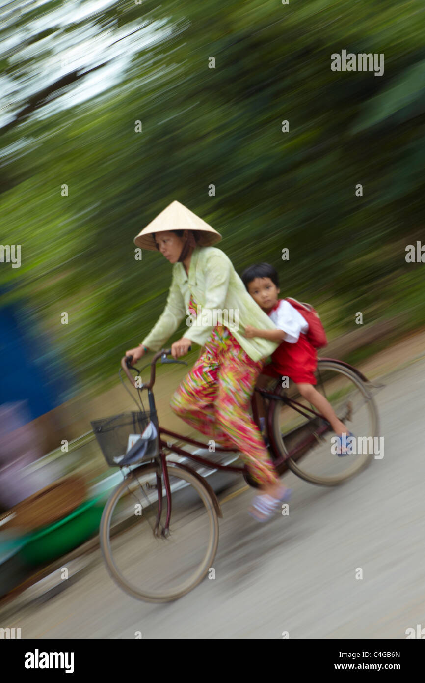 Una donna e bambino su una bicicletta, Delta del Mekong, Vietnam Foto Stock