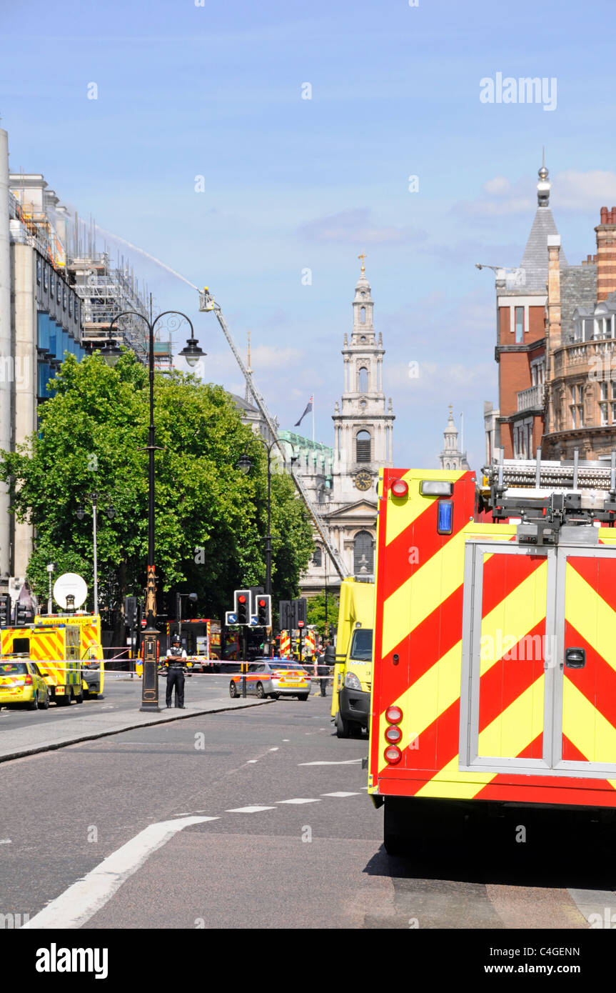 Servizi di emergenza dei vigili del fuoco e polizia veicoli ambulanza street scene pompiere mira acqua a tetto edificio fire & smoke Strand London REGNO UNITO Foto Stock