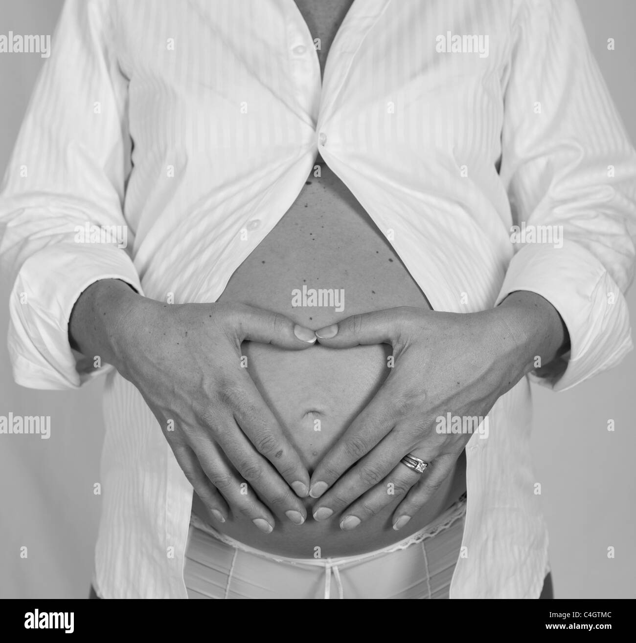 Una donna fanno forma di cuore sulla pancia in gravidanza Foto Stock
