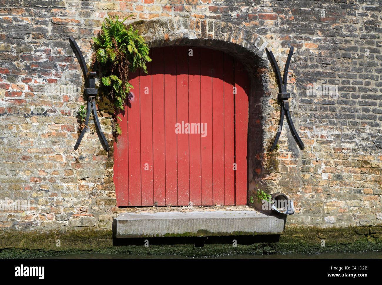 Minuscola apertura porta sul canale di Bruges, Belgio. Probabilmente utilizzato per caricare e scaricare le merci direttamente in casa. Foto Stock