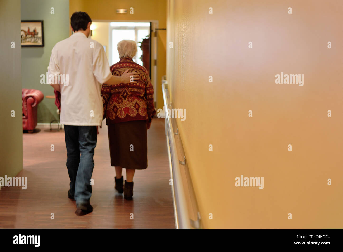 Old Lady e di personale infermieristico nel corridoio di una casa di cura Foto Stock