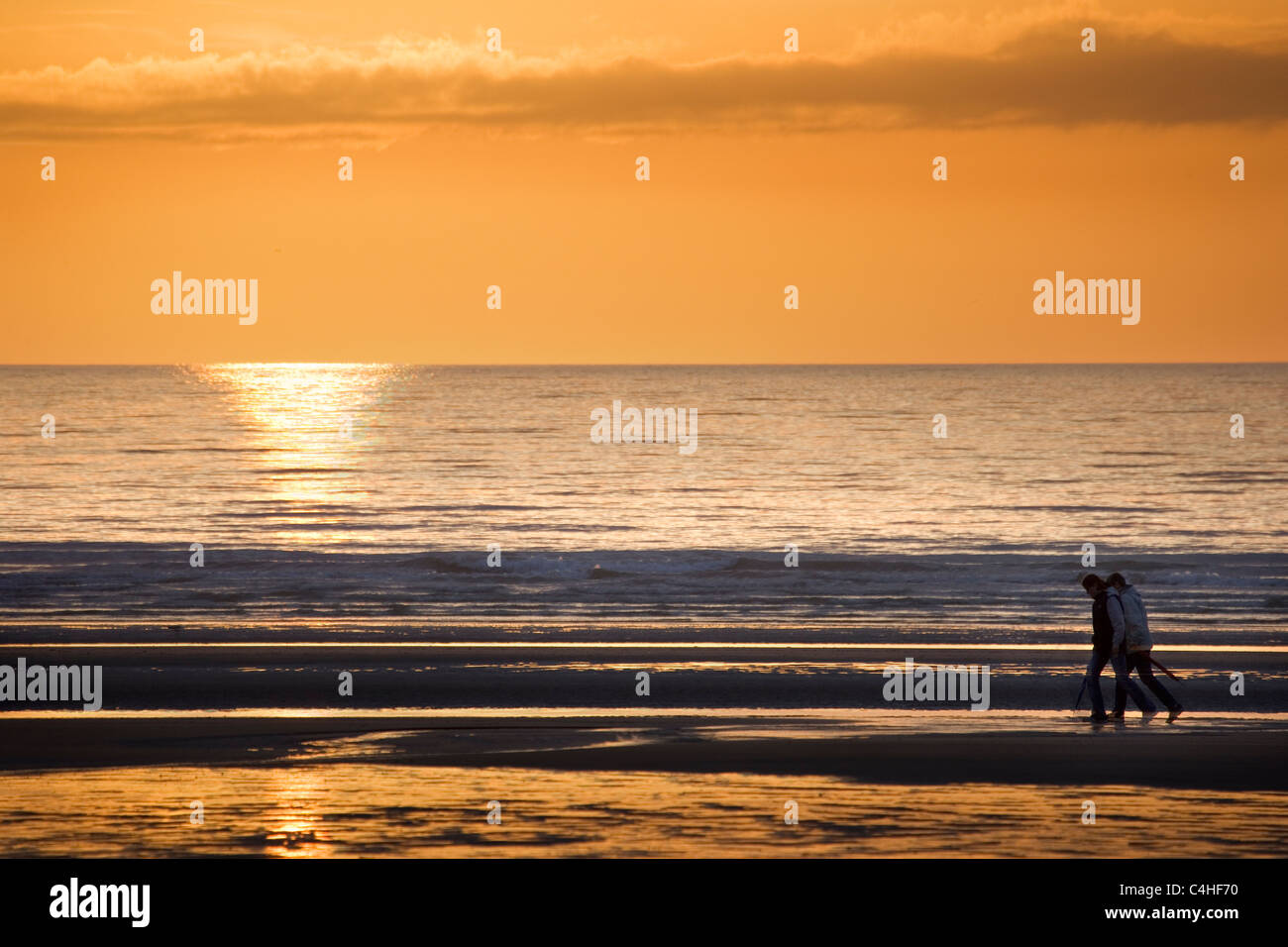 Un paio di camminare sulla spiaggia al tramonto Foto Stock